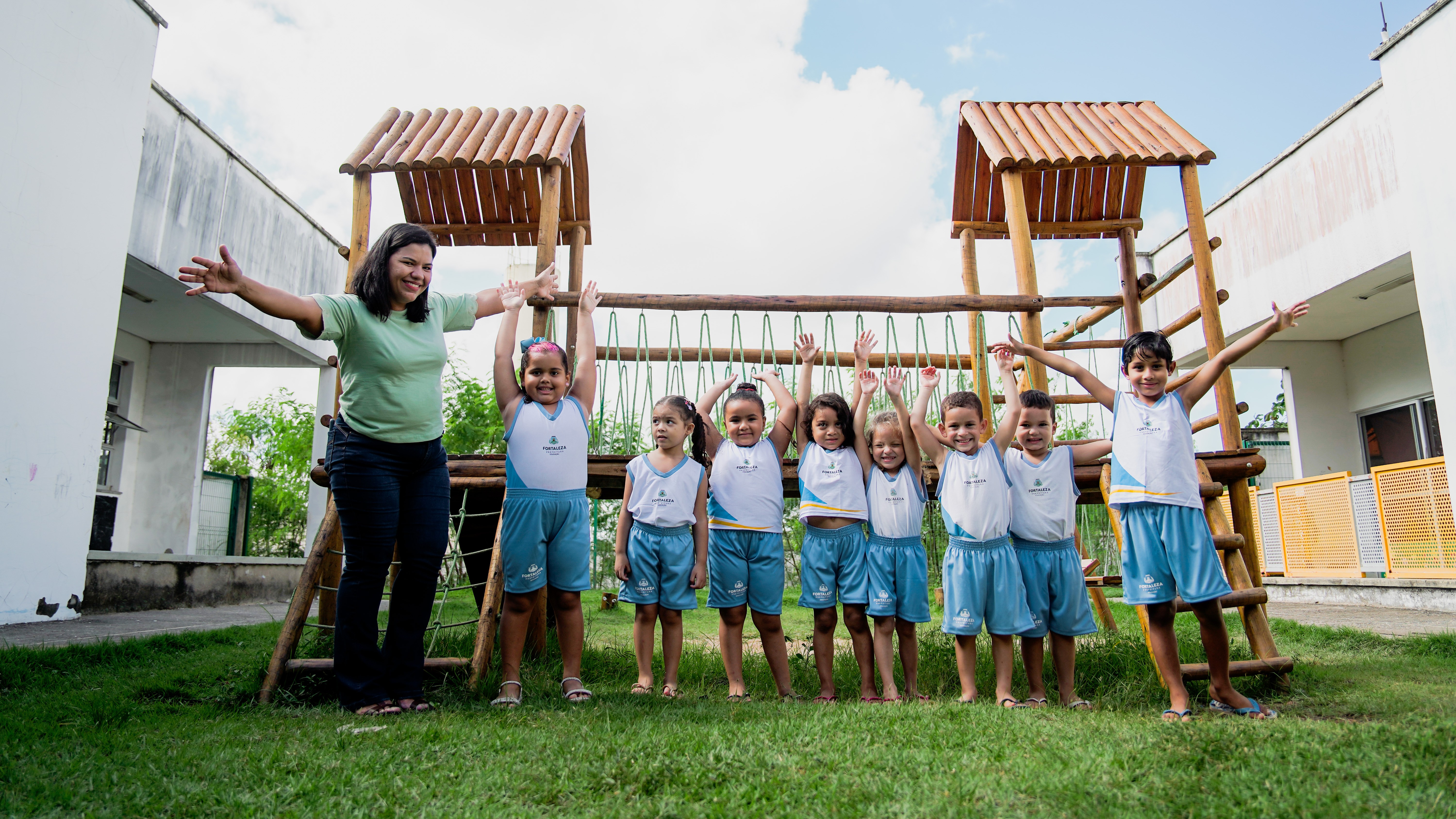 Crianças de uma creche e a professora posam para a foto no pátio da unidade 